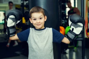 A spirited young contender stands poised and ready in his boxing gloves, exuding confidence in front of the towering punching bag at our distinguished Dubai boxing gym. This summer camp, he's geared up to unleash his potential and embrace the thrilling world of boxing.