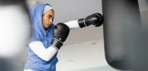 Within the walls of our elite boxing gym in Dubai, a dedicated and powerful woman embodies commitment and strength. Clad in a sleek blue hoodie and black boxing gloves, she delivers precise punches to the heavy bag. Her unwavering dedication to fitness remains steadfast, even as she gracefully observes Ramadan, showcasing the perfect blend of discipline and vitality that we nurture here.