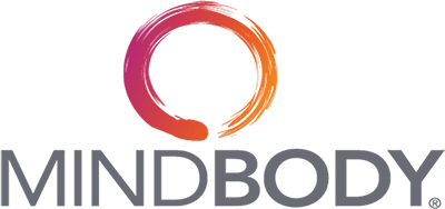 The image showcases the distinguished MINDBODY logo, featuring an elegantly crafted orange and red circle set majestically above the company name rendered in sleek gray text. This design subtly embodies the relentless energy and empowerment inherent in women's boxing, resonating with the spirit of determination and excellence cultivated at our premier boxing gym in Dubai.