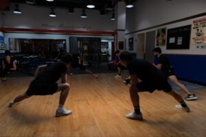 Athletes focused on precision floor lunges across the studio hardwood at our Dubai boxing facility.