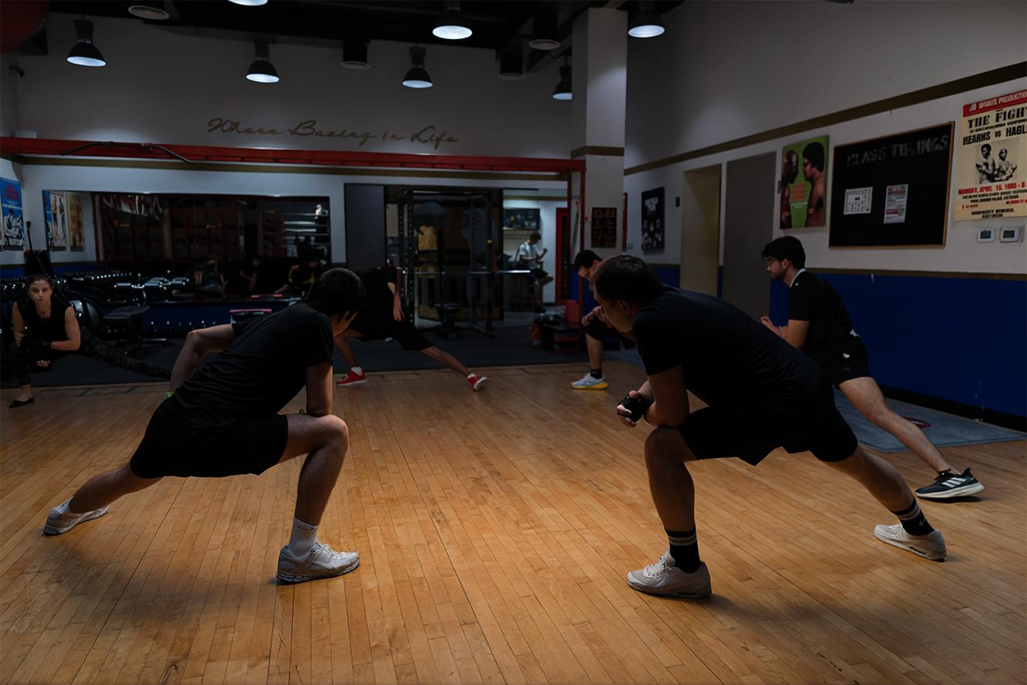 Athletes focused on precision floor lunges across the studio hardwood at our Dubai boxing facility.