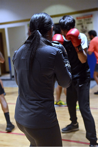 Under the precision lighting of our elite Dubai boxing gym, two dedicated fighters engage in an intense sparring session. One, with striking red gloves symbolizing their commitment and prowess, moves with calculated agility against their formidable partner. Surrounding them are other driven athletes honing their skills, each a testament to the spirit and excellence that define our specialized training environment. Here, under the glow of fluorescent lights, champions are forged.